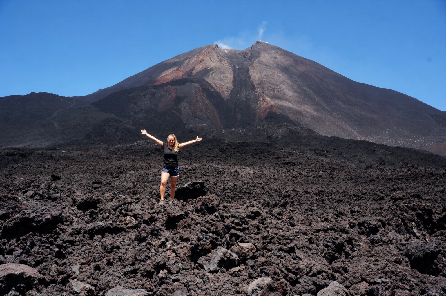 Hiker standing on Pacaya lava field with the volcano summit behind